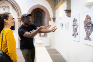 Two people looking at artworks on the wall of The Church at Edinburgh Deaf Festival