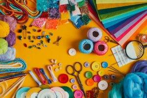 Various colourful arts and craft supplies laid out on a yellow table.
