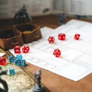 A table with various dice and pieces of paper. There are figurines of mythical creatures.