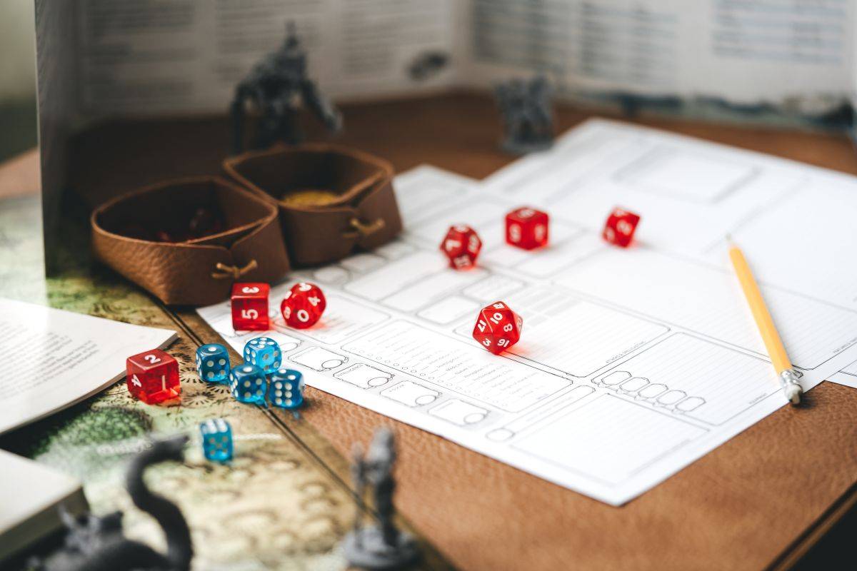 A table with various dice and pieces of paper. There are figurines of mythical creatures.