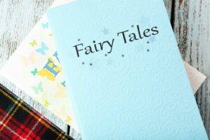 Two fair tale book sitting on a table with a tartan blanket