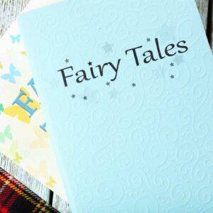 Two fair tale book sitting on a table with a tartan blanket