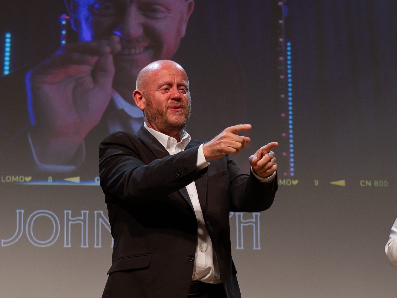 Comedian John Smith pointing to the audience with both hands.