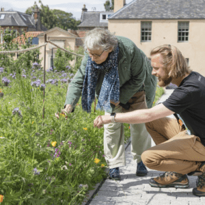 Two people at Royal Botanic Garden Edinburgh kneeling down to feel some flowers.