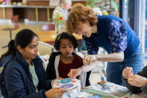 People being shown how to embroider in a workshop setting.