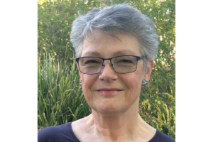 A woman with short grey hair and glasses.