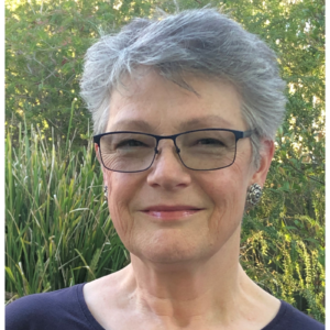 A woman with short grey hair and glasses.