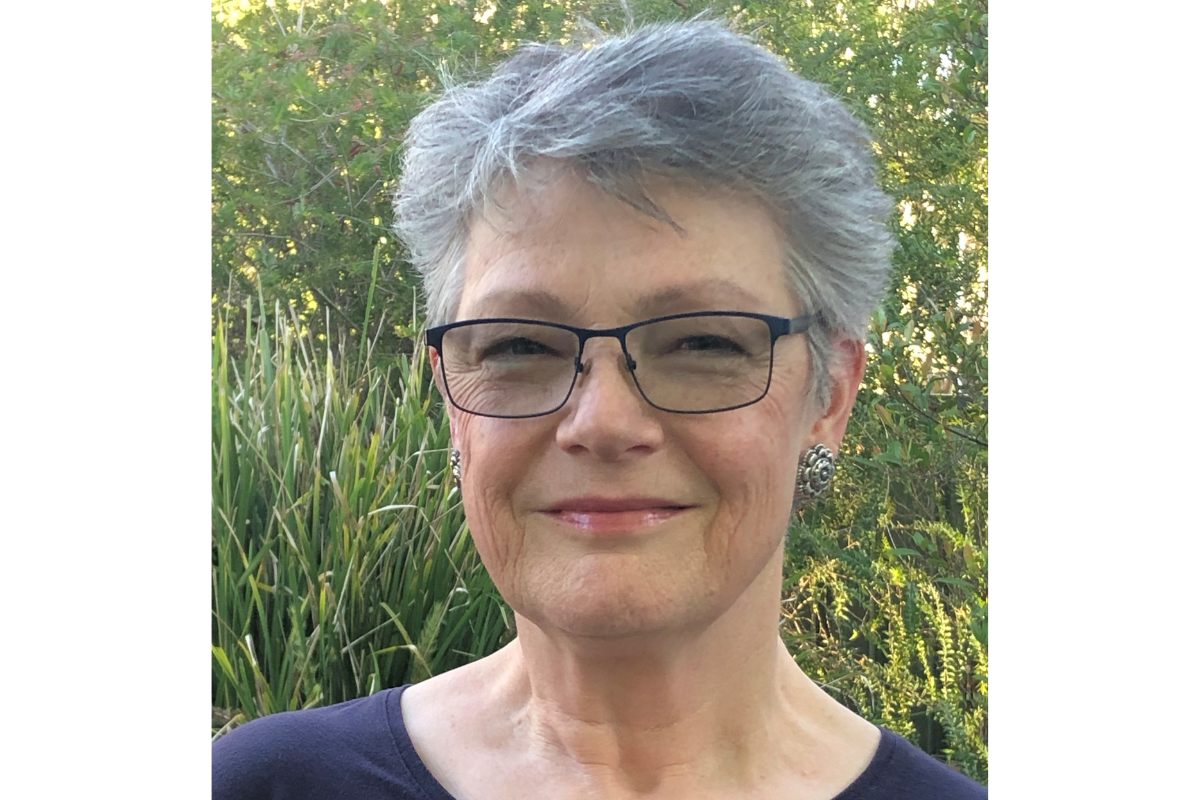 A woman with short grey hair and glasses.