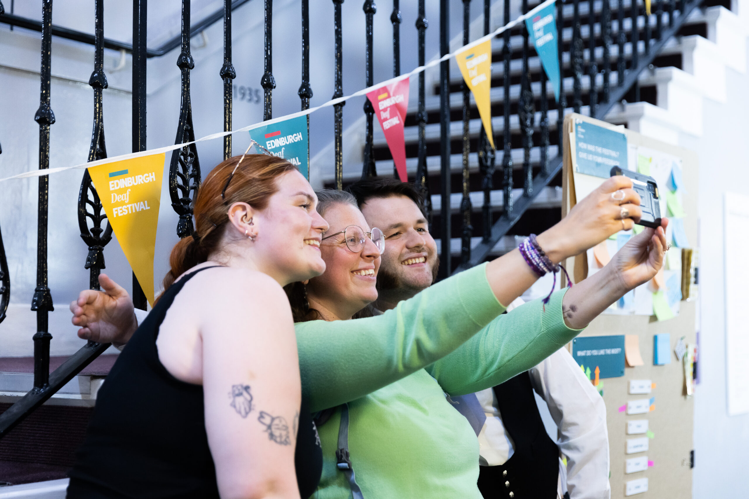 A group of people standing in front of a staircase taking a selfie.