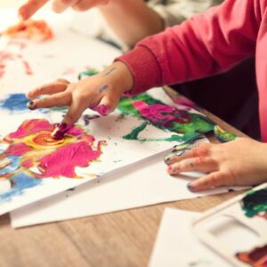 Children finger painting on paper.