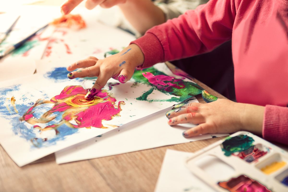 Children finger painting on paper.