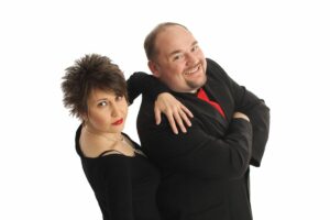 Magic Morgan and Lilliana. Two people standing beside each other. The woman has her hand on the mans shoulder and his arms are crossed.
