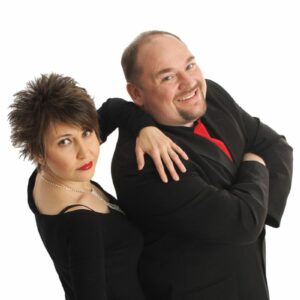 Magic Morgan and Lilliana. Two people standing beside each other. The woman has her hand on the mans shoulder and his arms are crossed.