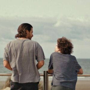 Film poster for Milano - A man and a boy standing looking out at sea.