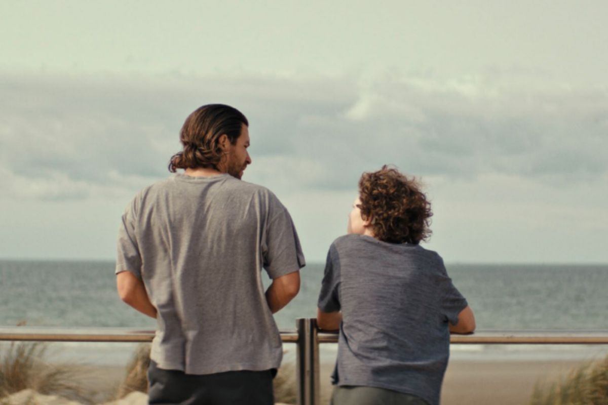 Film poster for Milano - A man and a boy standing looking out at sea.
