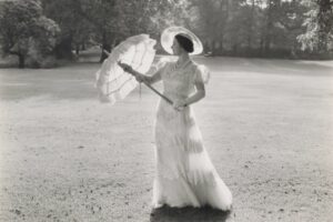 Black and white photo of the queen mother dressed in white holding a white umberella.
