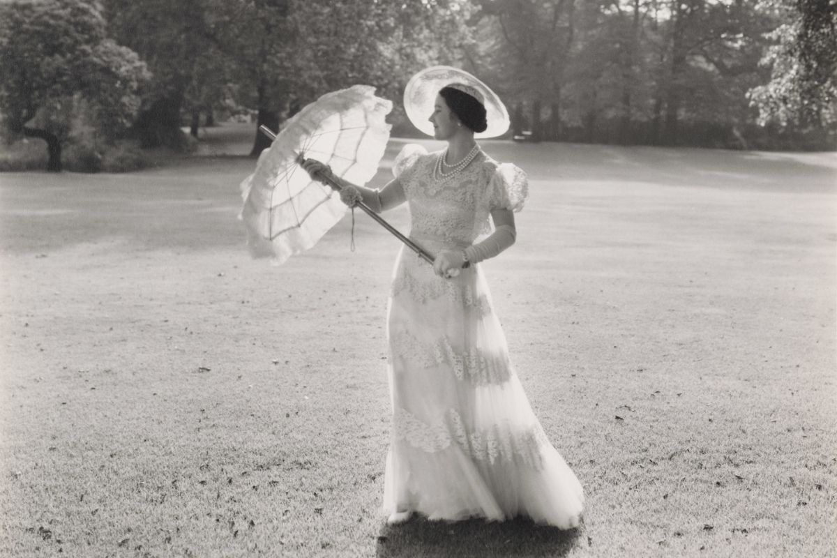 Black and white photo of the queen mother dressed in white holding a white umberella.