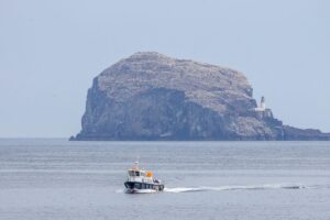 A small boat in the water in front of an island