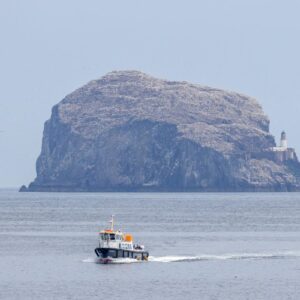 A small boat in the water in front of an island