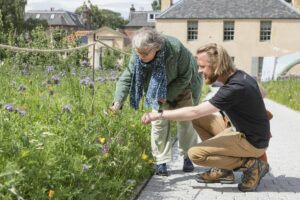Royal botanic tour. Two people are standing beside a garden looking at the plants.