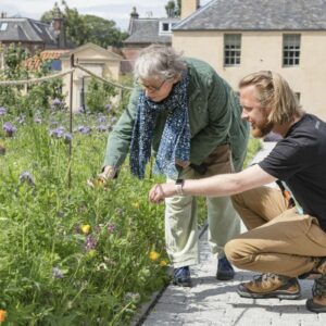 Royal botanic tour. Two people are standing beside a garden looking at the plants.