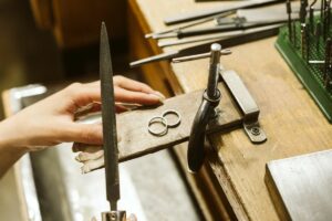 A silver ring on a workbench with someone holding tools