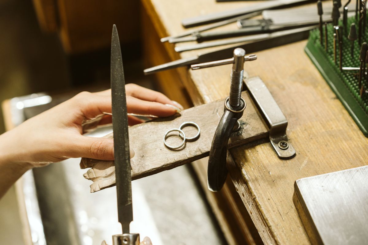 A silver ring on a workbench with someone holding tools